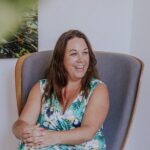 een foto van collega Christa, lachend en zittend in een stoel